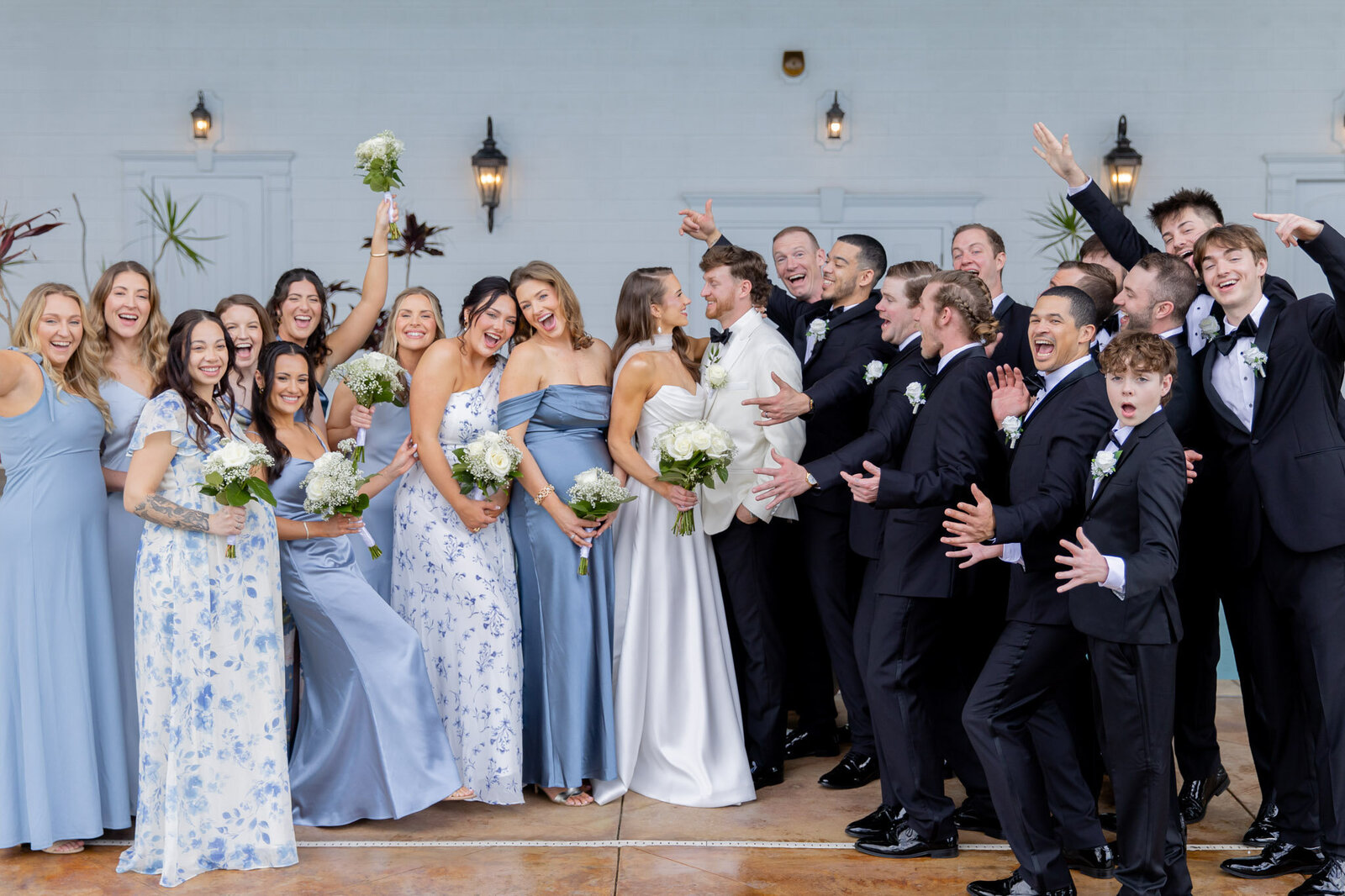 A bride and groom look into each other's eyes as their bridesmaids and groomsmen surround them celebrating.