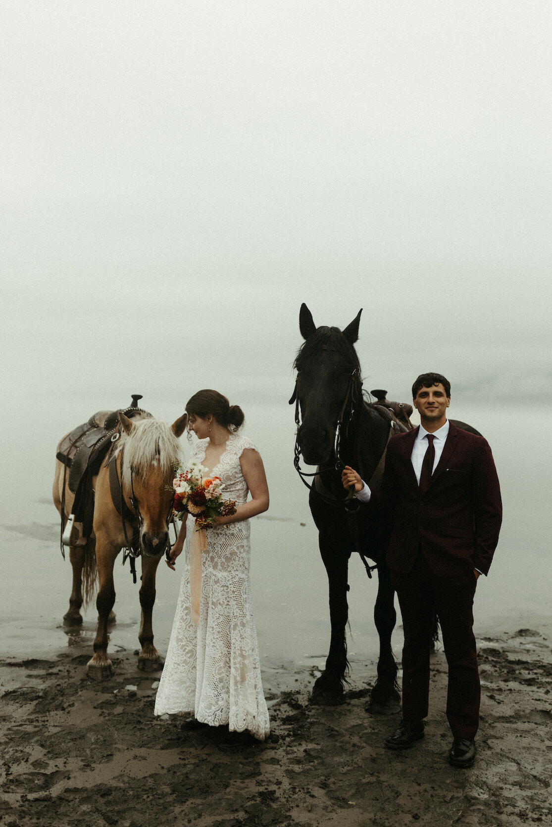 Couple standing with their horses next to a lake