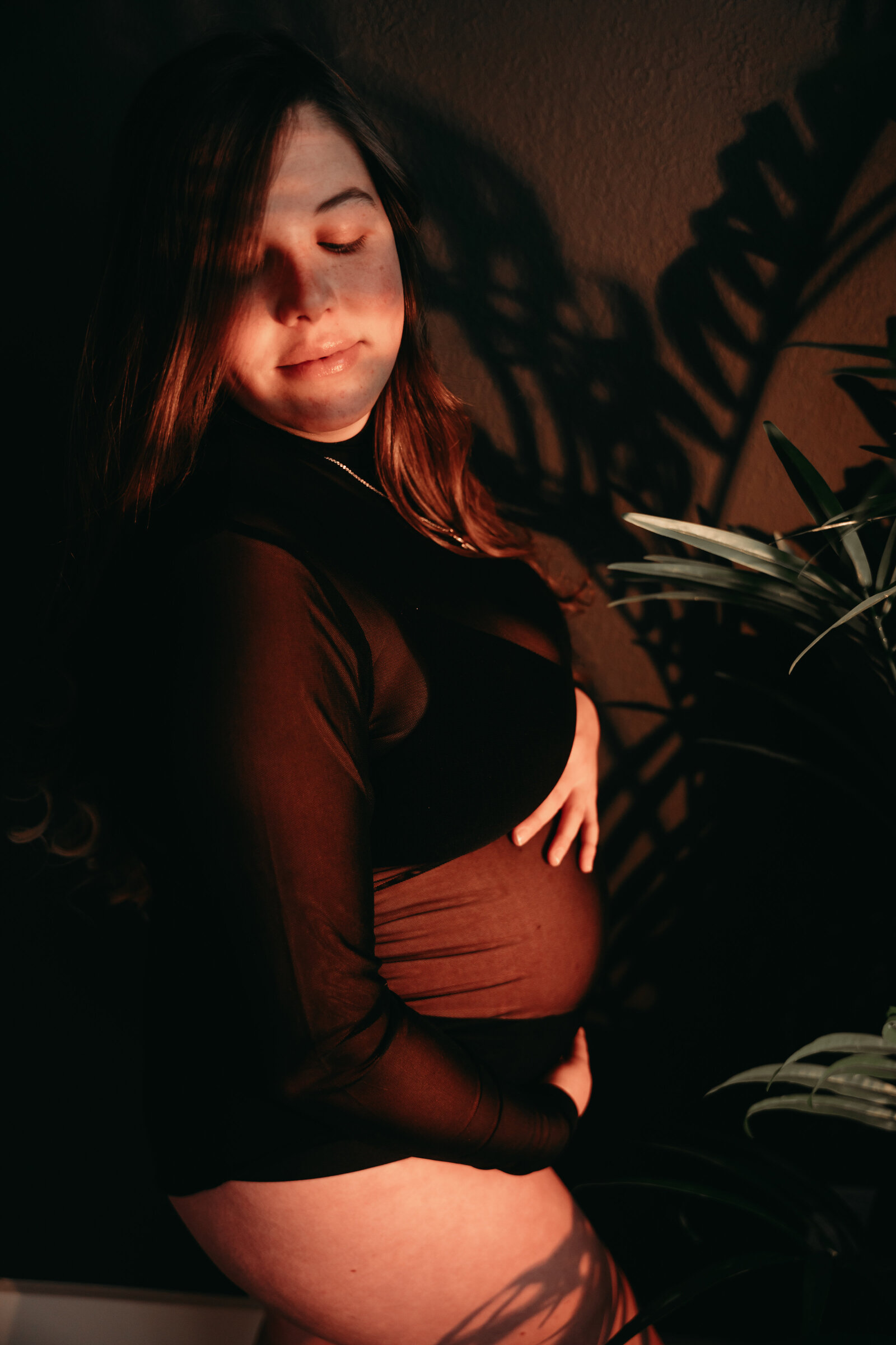 Pregnant woman embracing her belly during a boudoir session in Kansas City