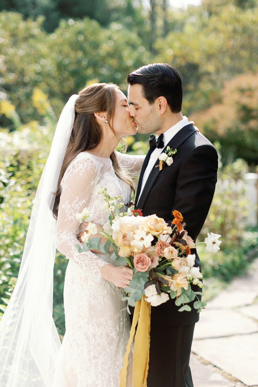 bride and groom kissing holding bouquet