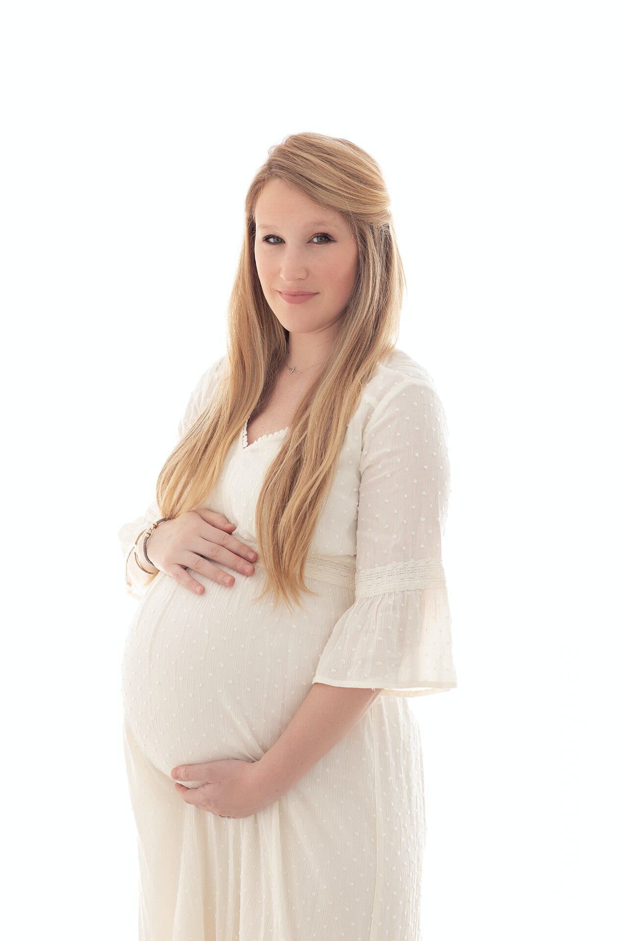 Serene maternity portrait of a woman in a soft white gown