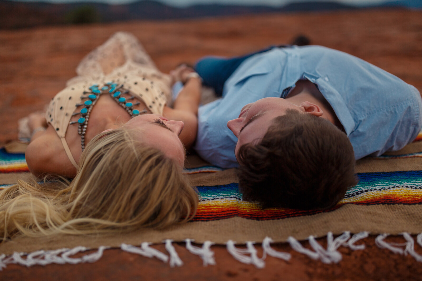 couple laying on colorful blanket on red rocks in sedona