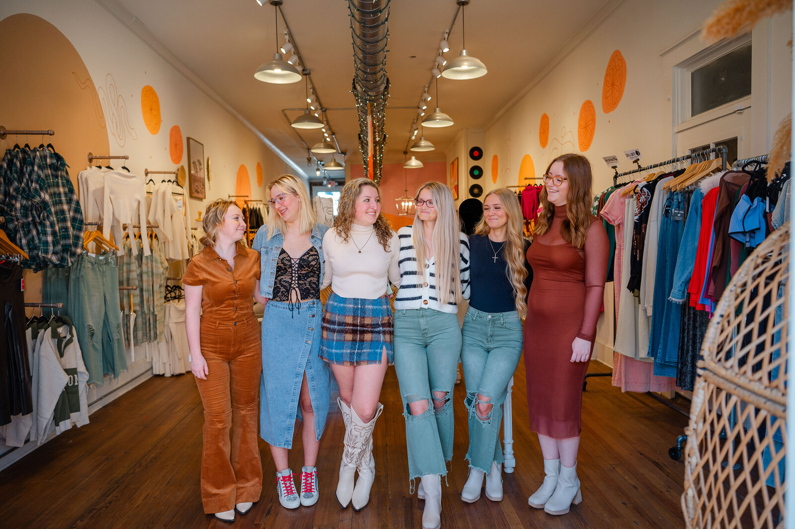 Group of high school senior girls stand together in the Peachy Keen Boutique after modeling their outfits in downtown Monroe, GA