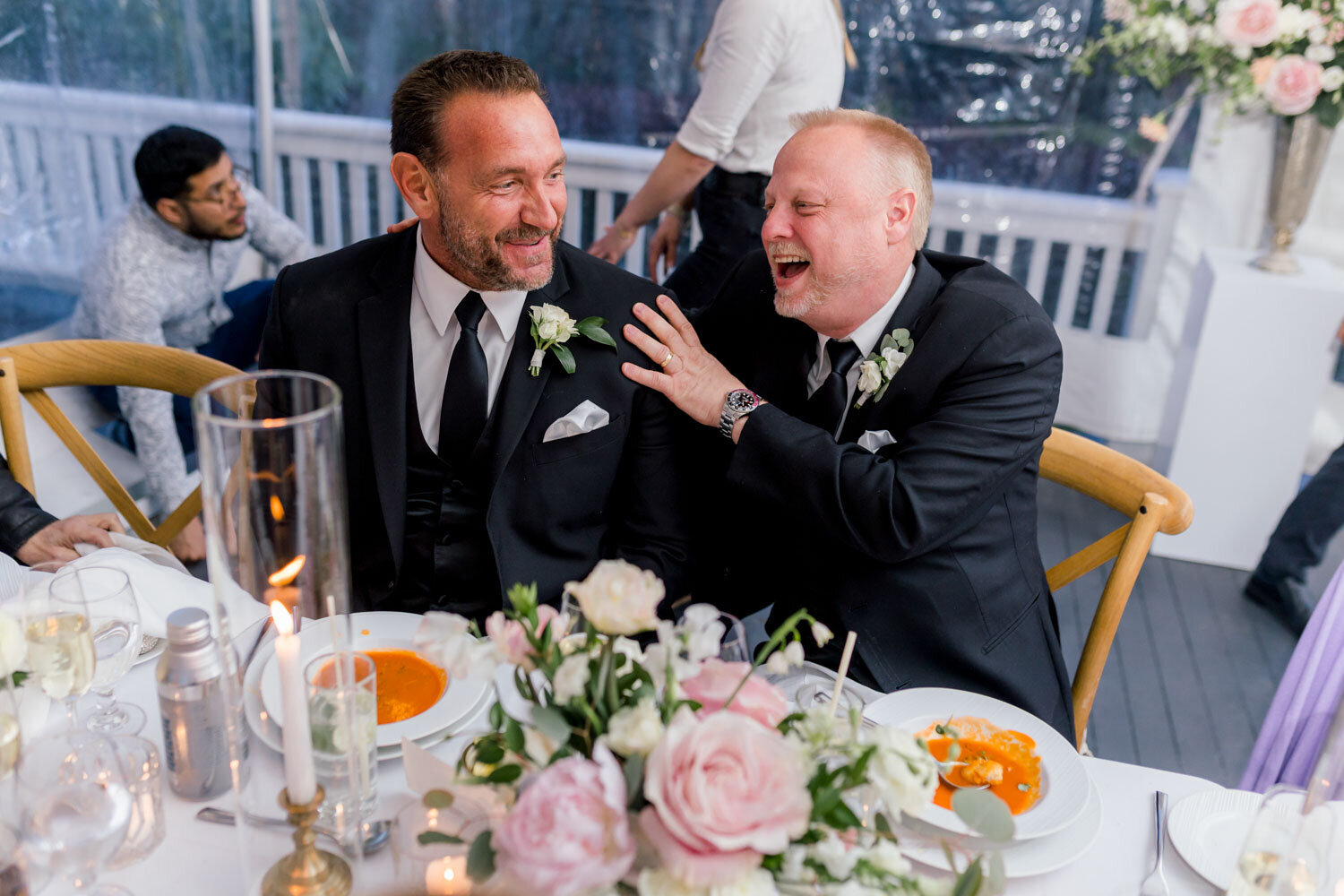 Two men laughing at a wedding reception