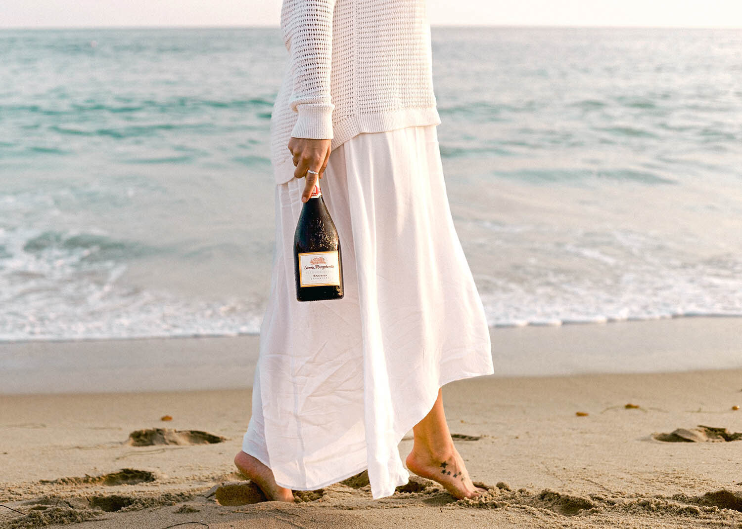 Wine at the beach with a girl walking by the ocean