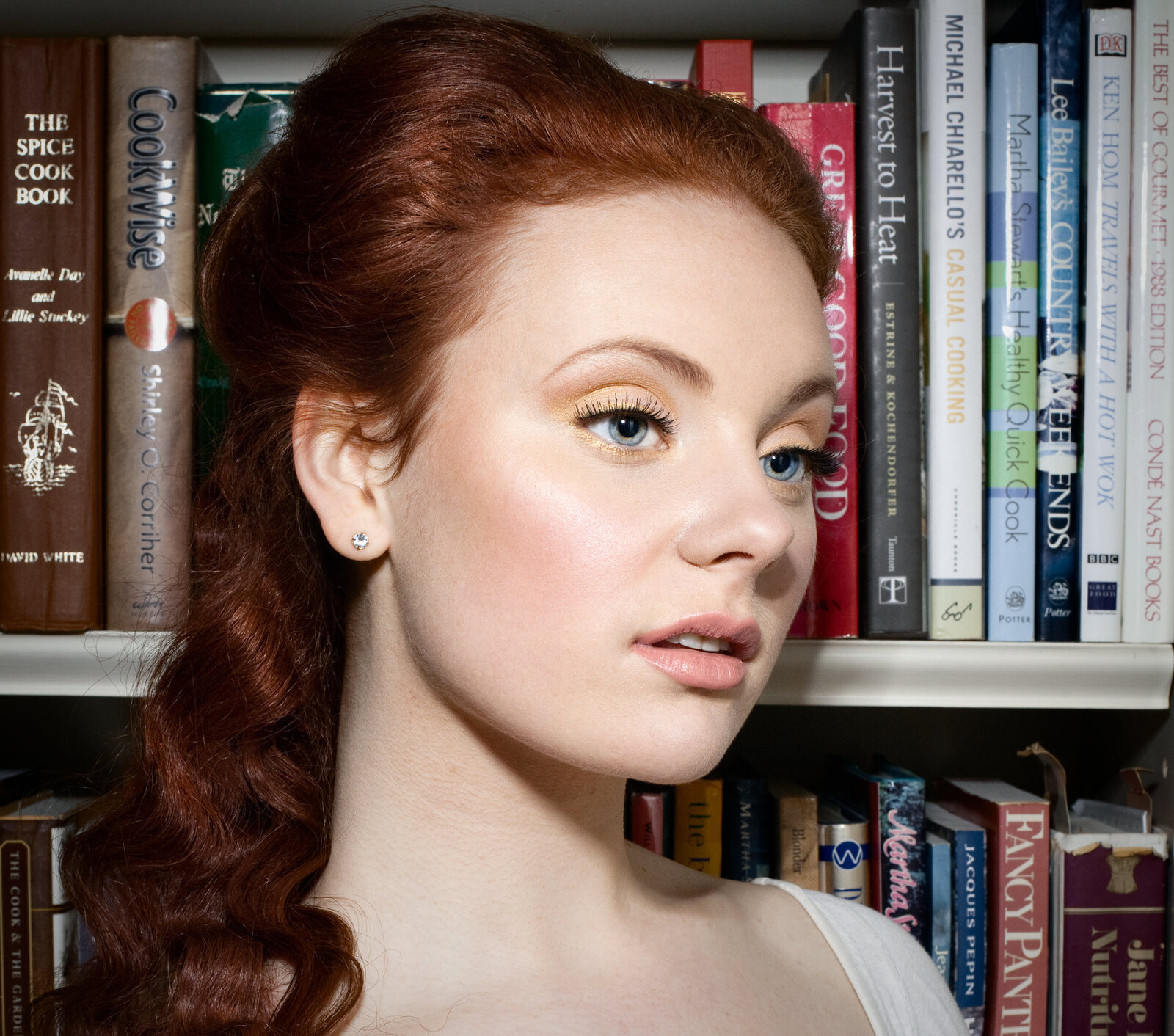 makeup for a model  standing in front of a bookcase