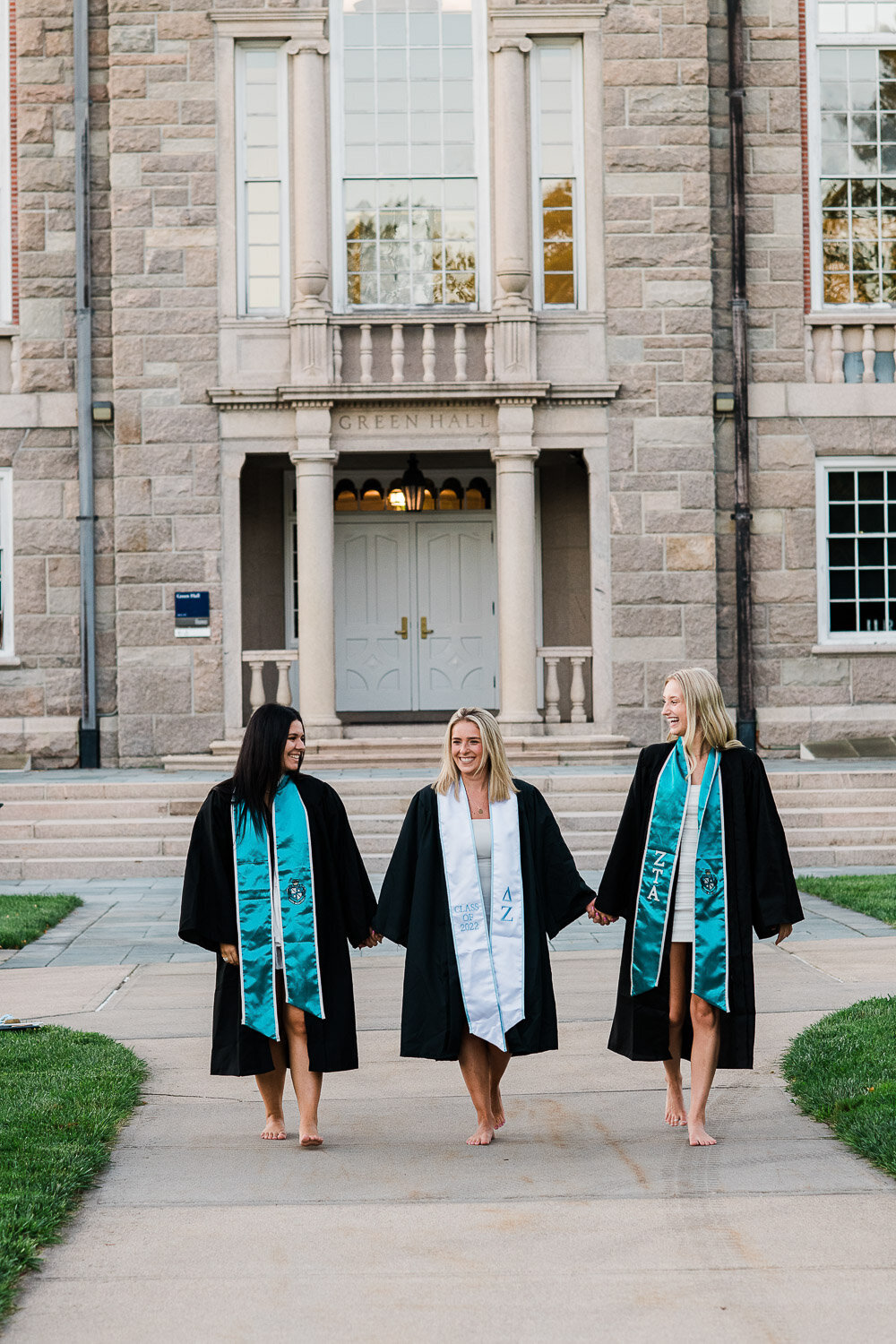 grad girls in robes with sashes walking holding hands