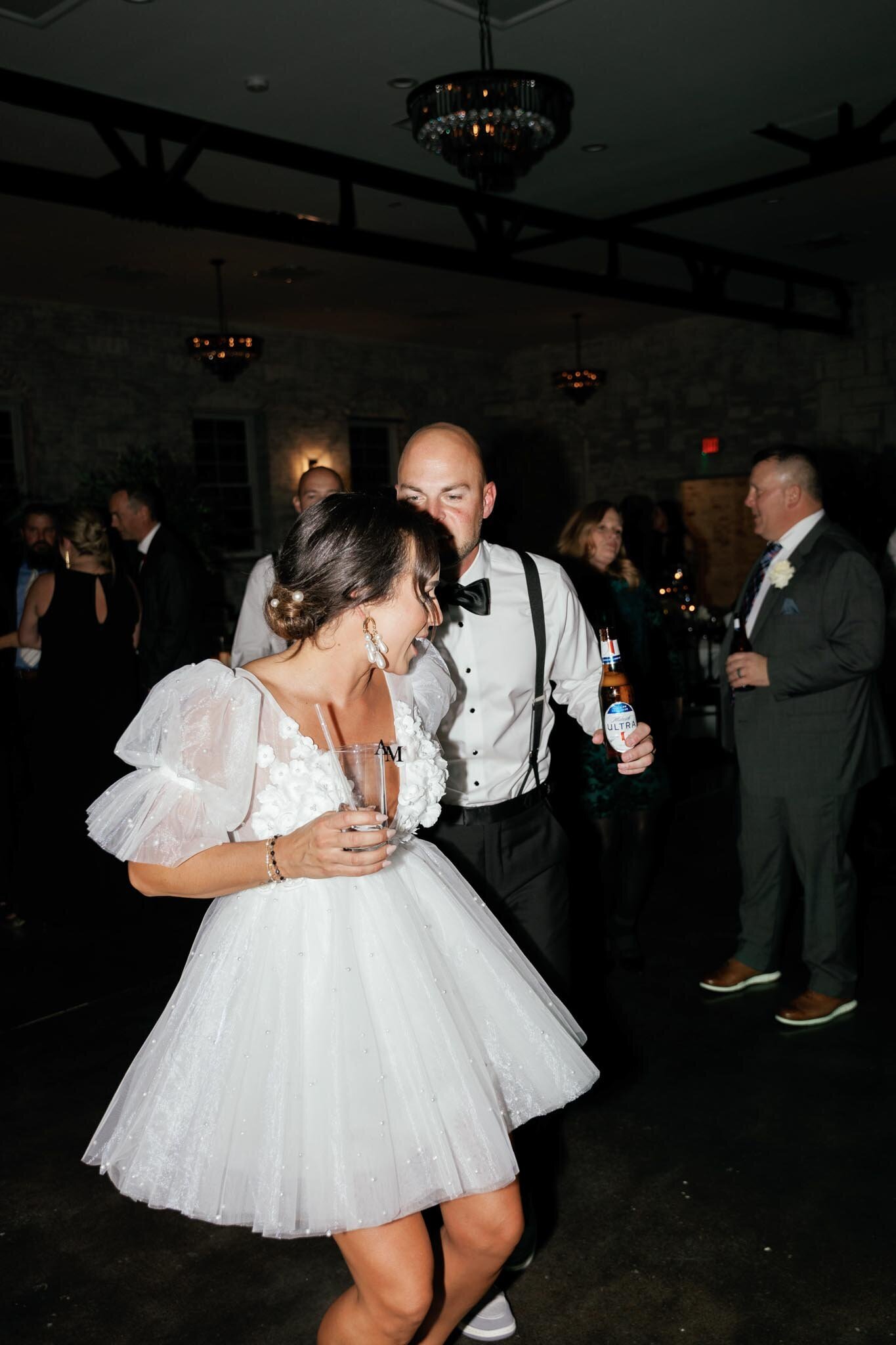 bride and groom dances all night in their wedding party holding a drink 