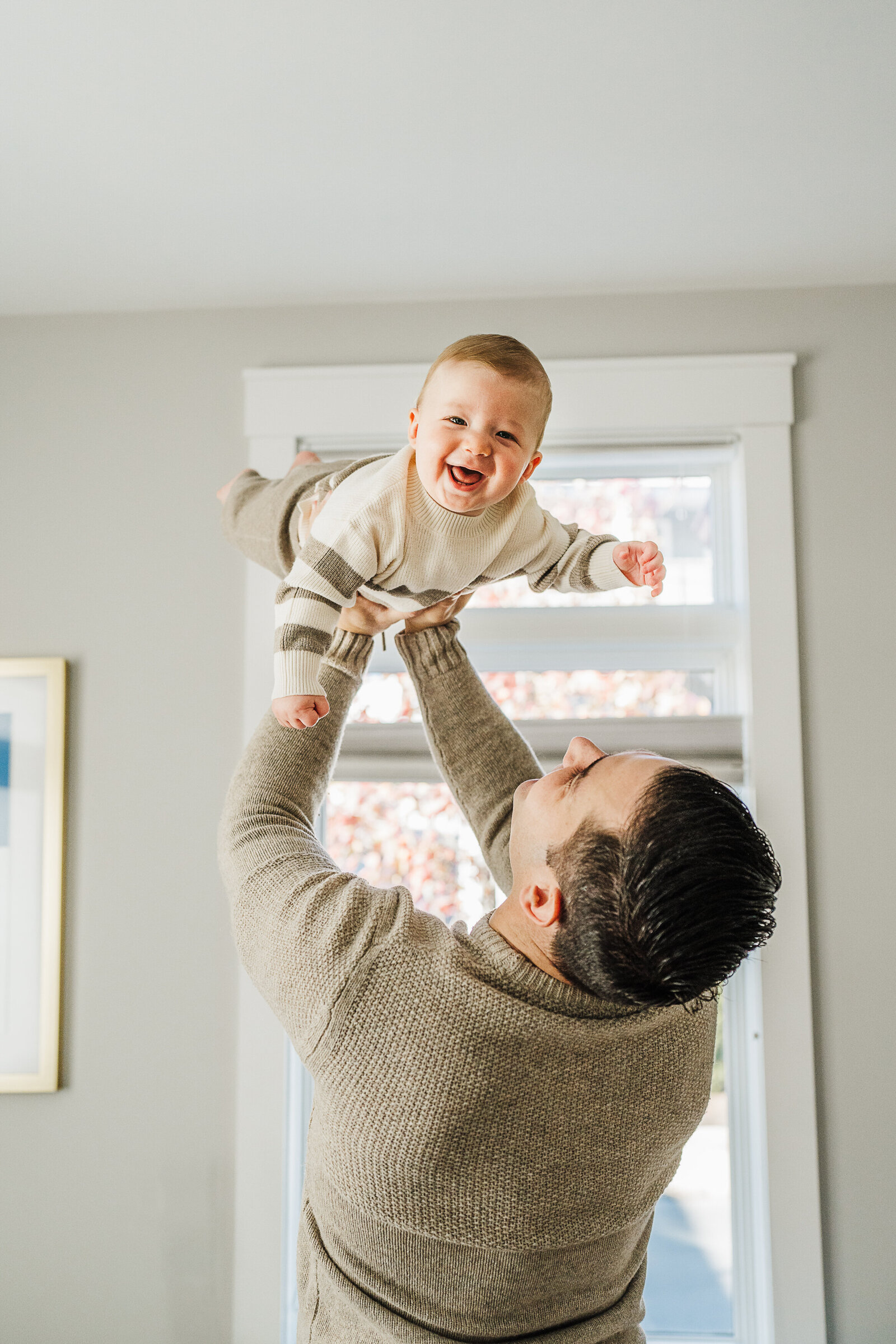 dad lifts baby son in air who laughs
