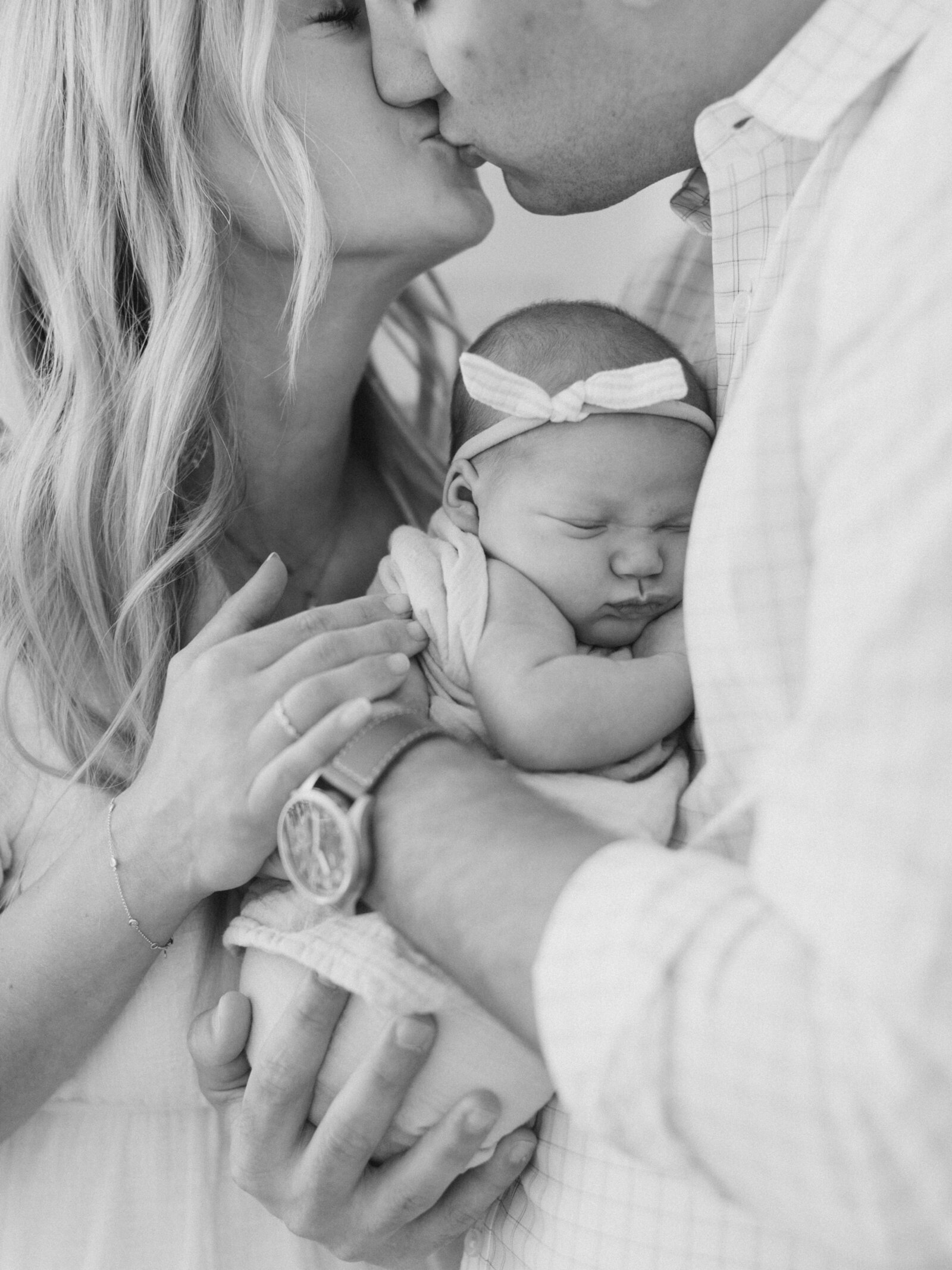new mom and dad kissing each other and holding their new baby girl