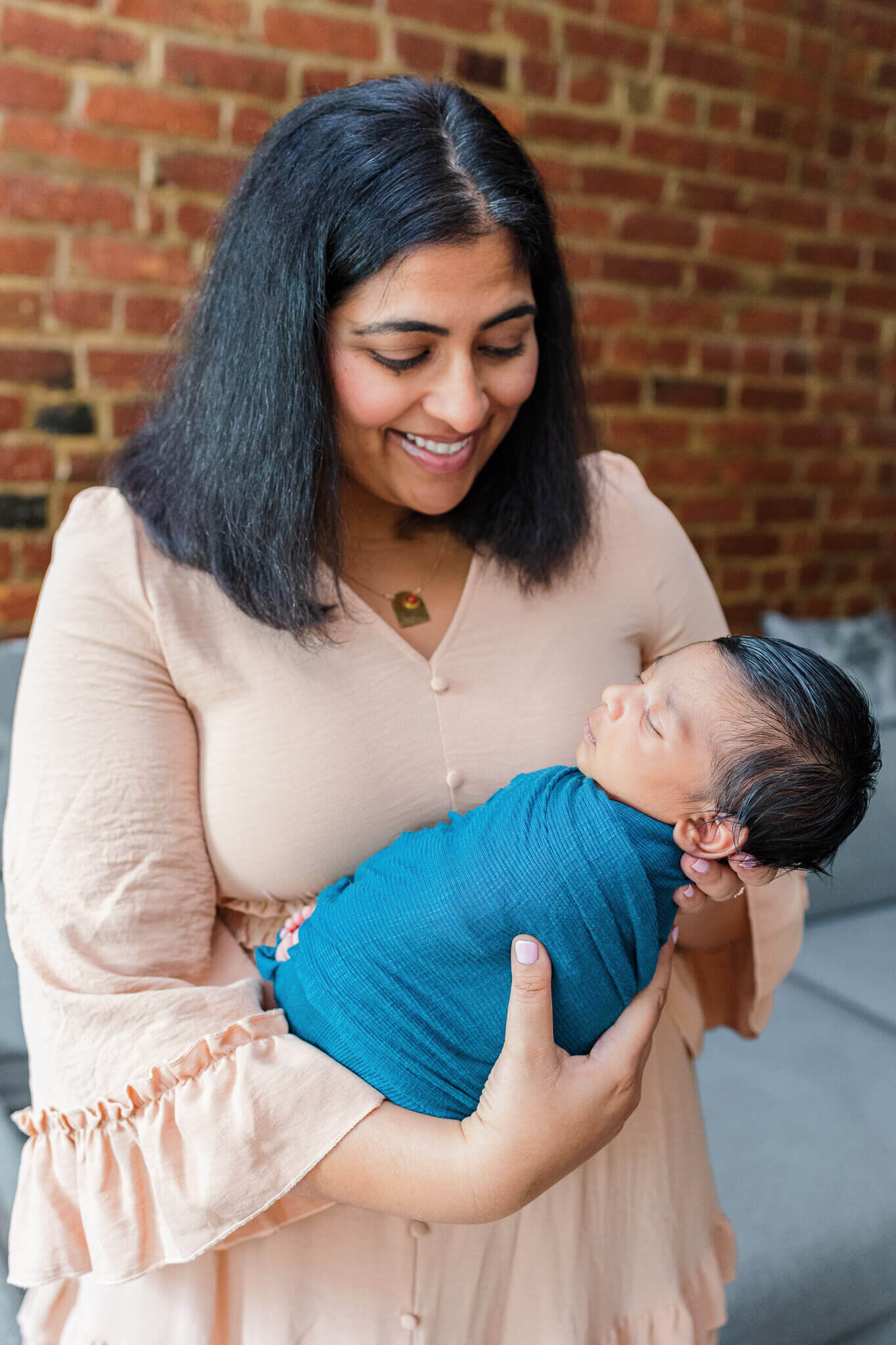 A mom holding her newborn son and smiling at him.