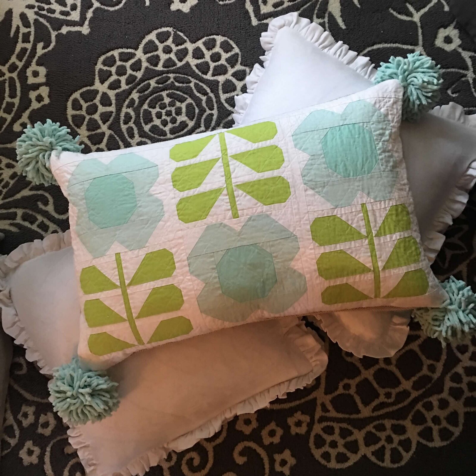 Handmade and quilted pillow with three flowers with long stems.