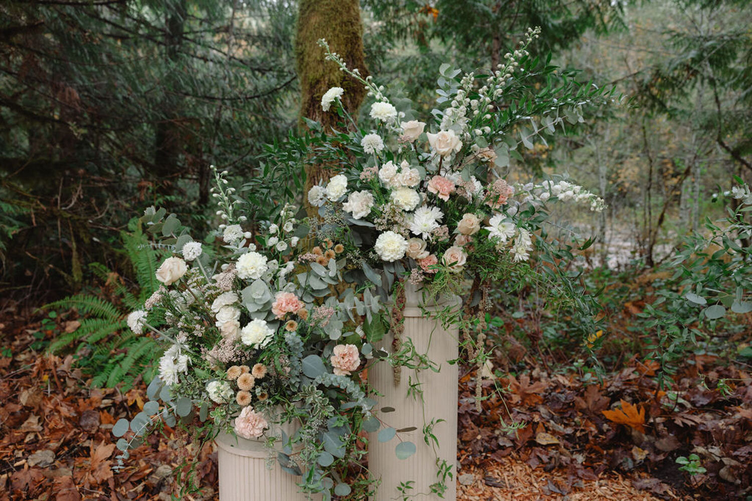 Matching floral arrangements displayed in tall cream vases