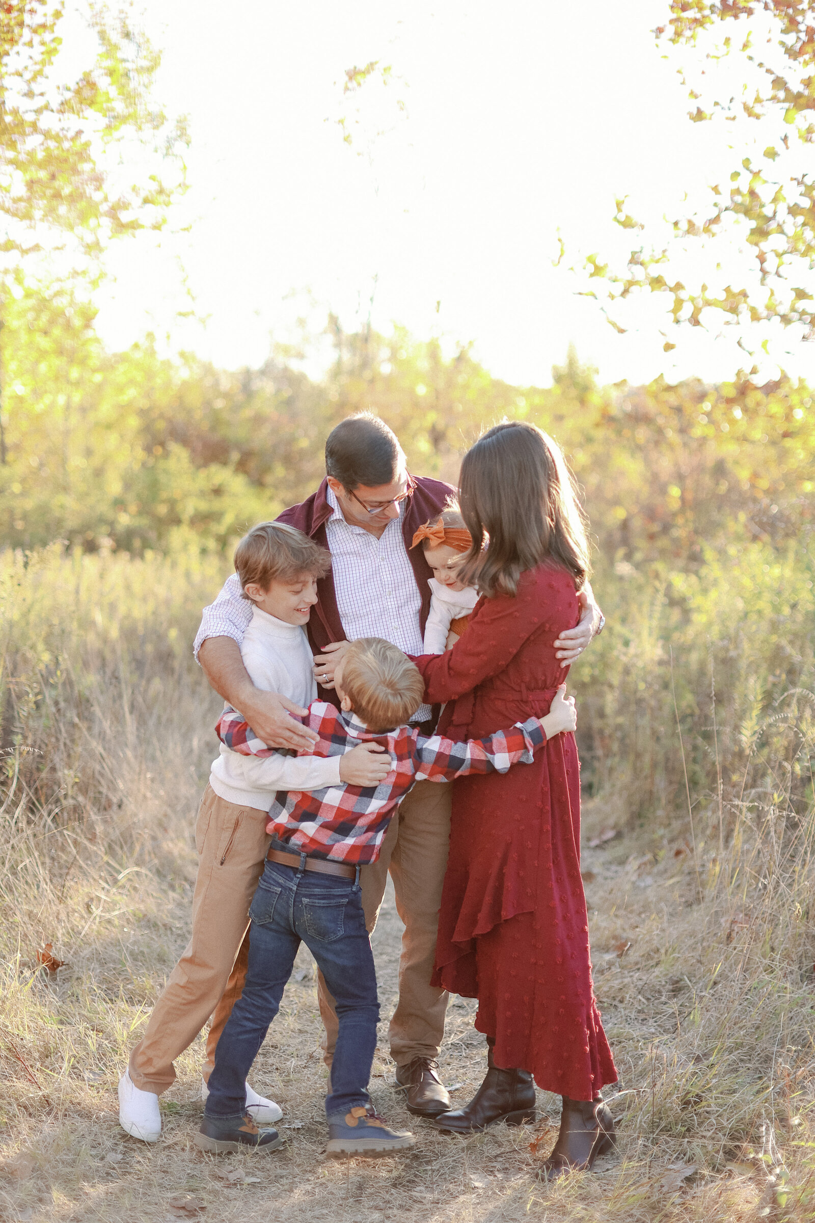 family hugging during fall mini sessions at Founders Park in Carmel, Indiana