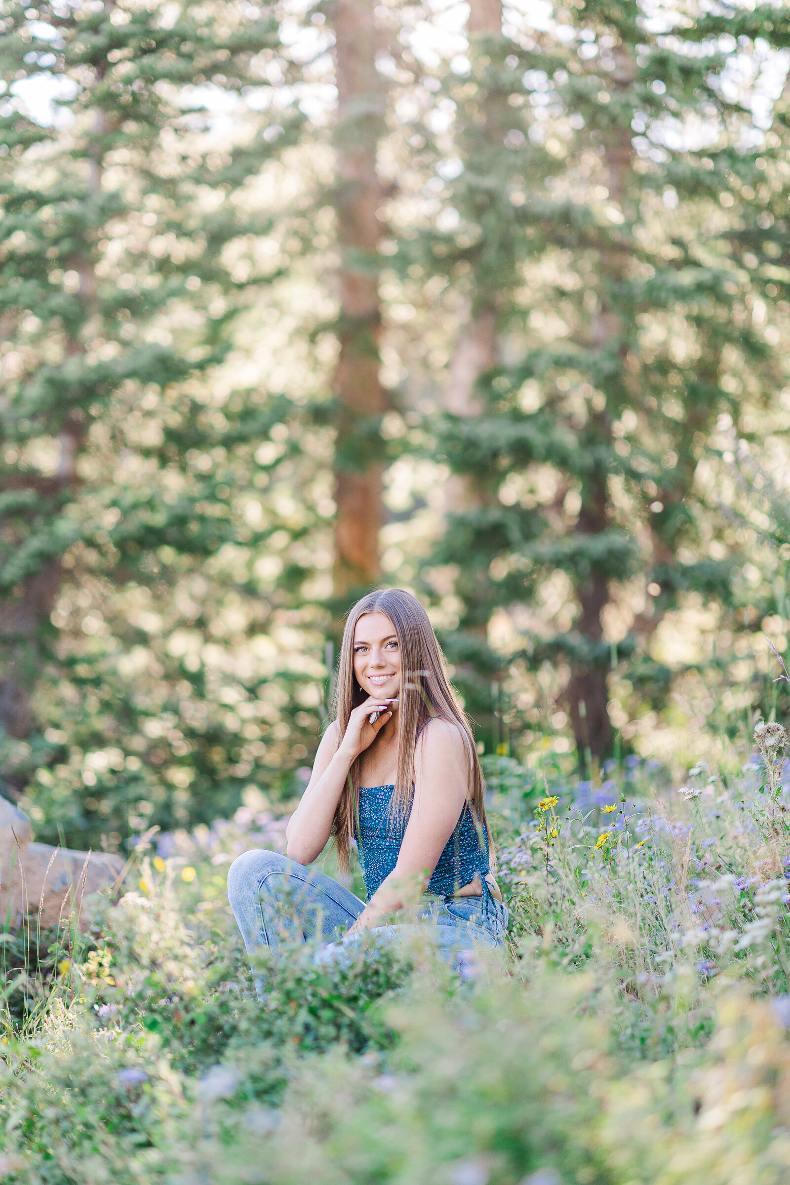 Senior squats with hand under chin for senior pictures