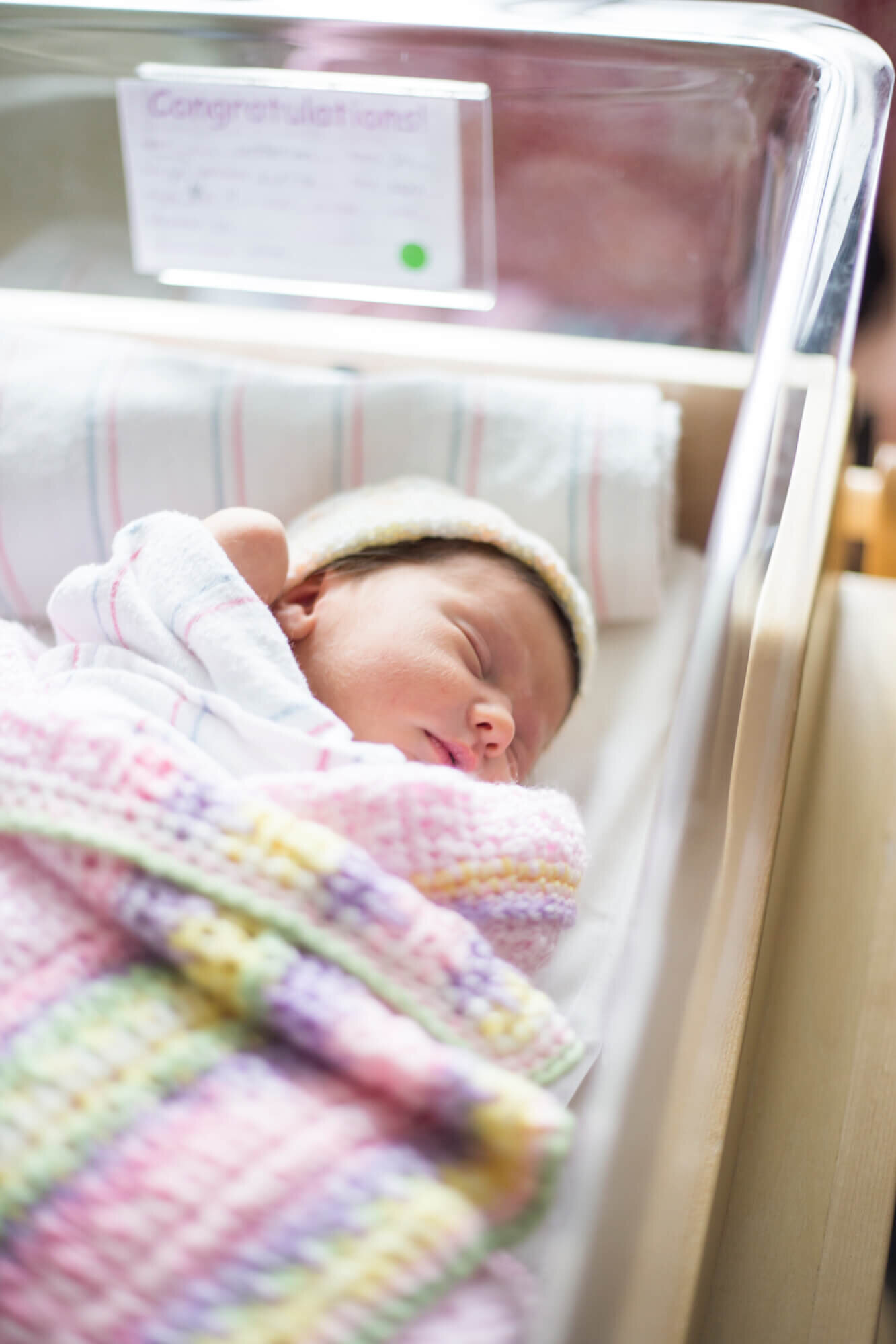 Fresh 48 image of newborn baby girl wrapped in knitted blanket in hospital baby bed