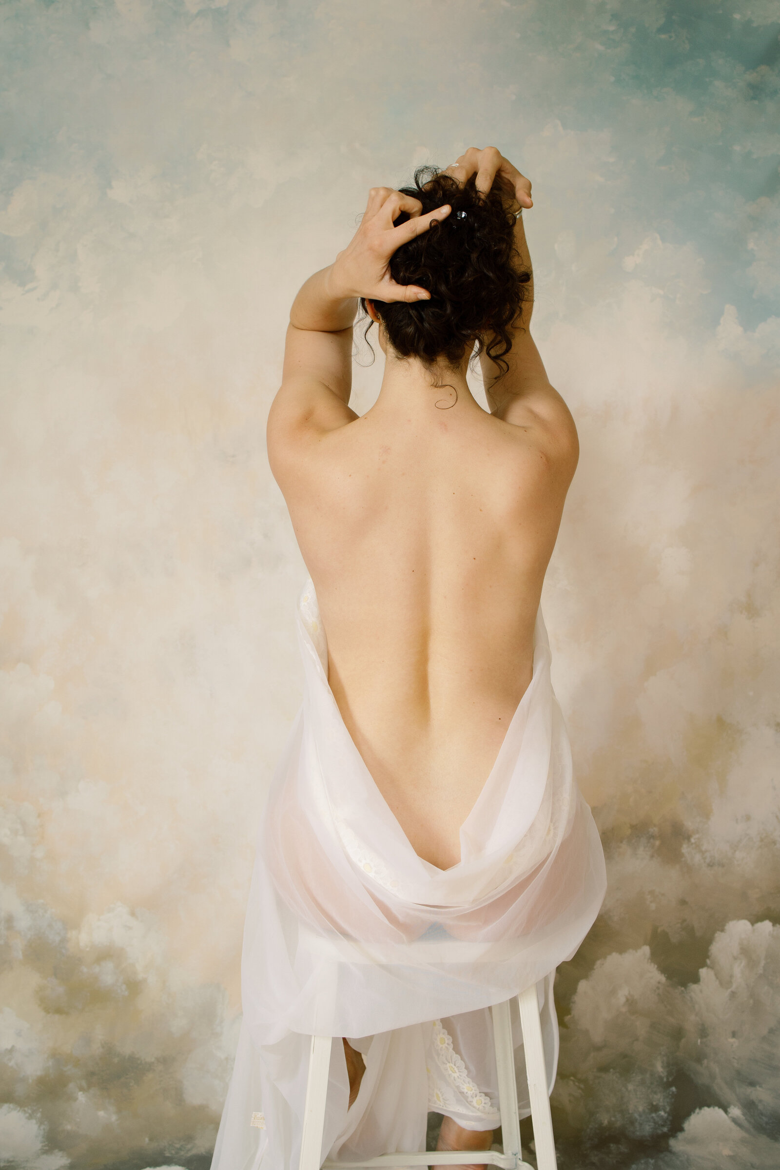 Back of nude woman wrapped in white sheet