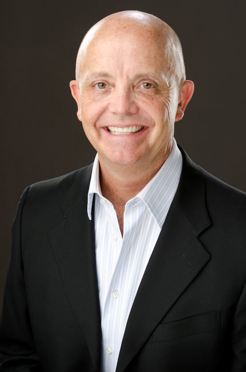 Man in suit smiling at center camera for his professional headshot