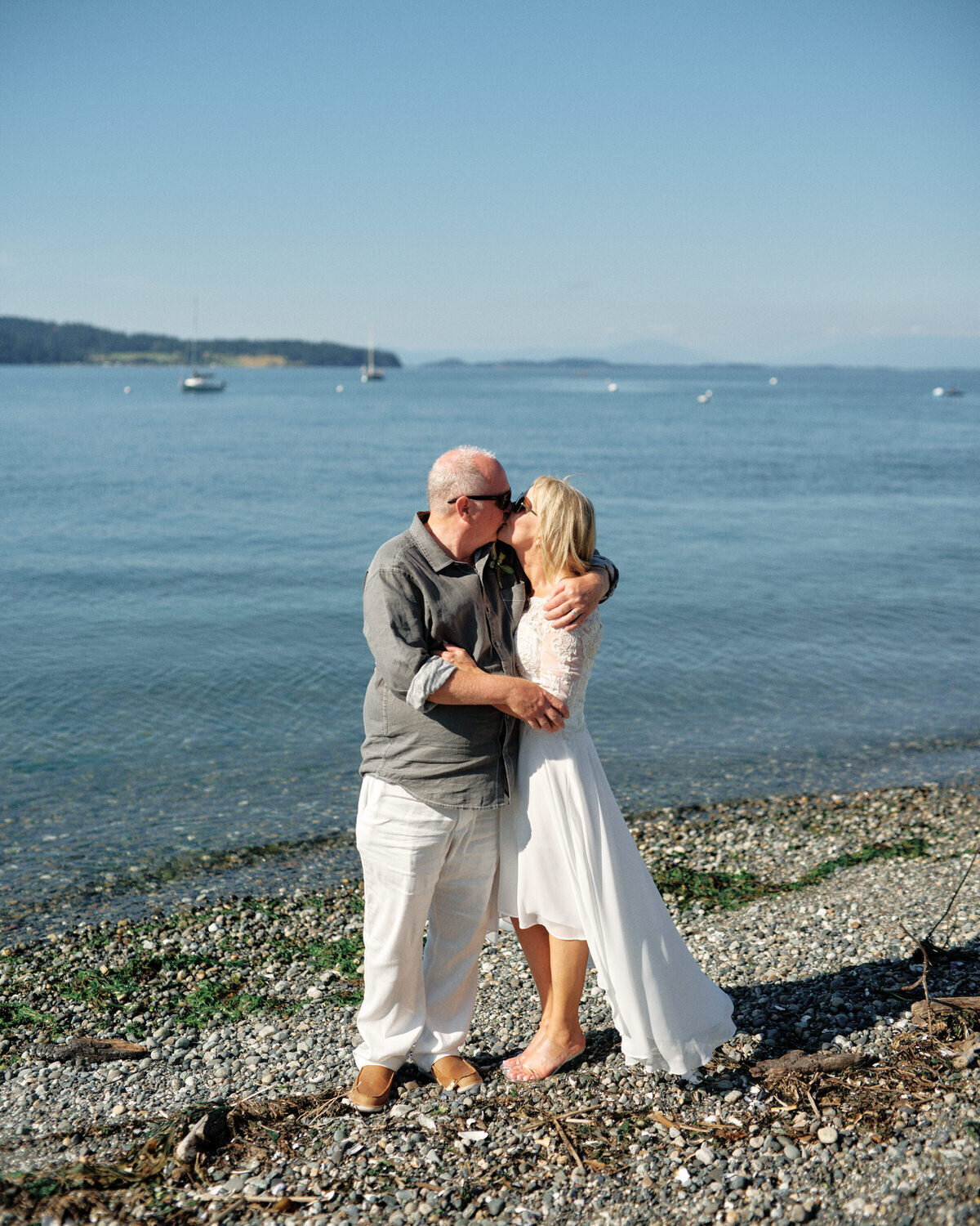 Bride and groom kiss on the banks of the puget sound