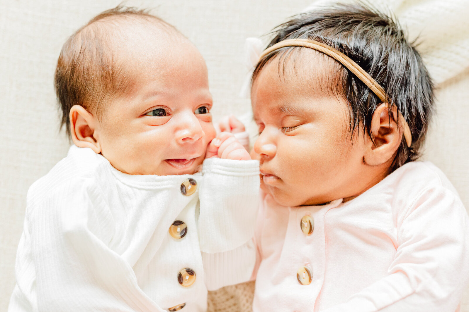 One newborn sleeps while her twin brother smiles