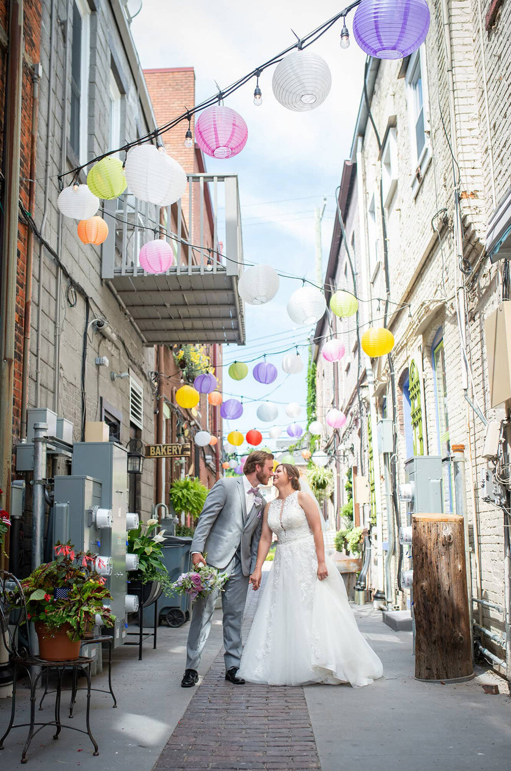 bride and groom kiss in alley with colored chinese paper lanterns