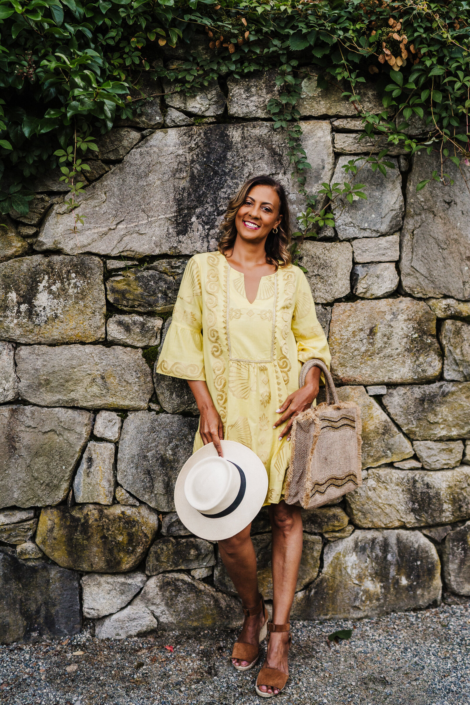 woman in yellow dress leans against stone wall