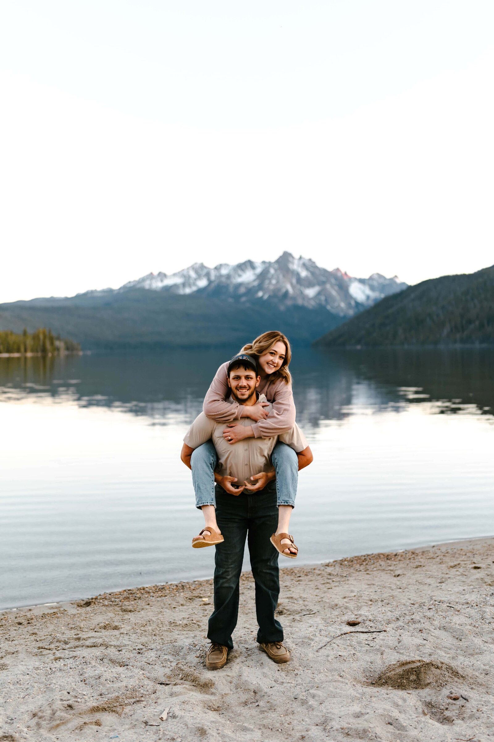 A couple standing on the shore of Redfish Lake in Idaho during their engagement photo session