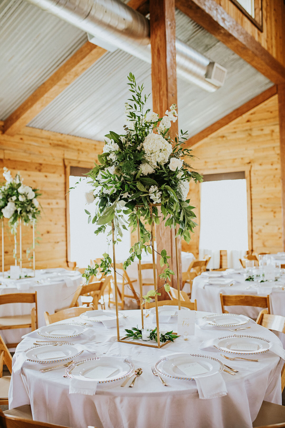 tall gold stand with organic white flowers with lush greenery