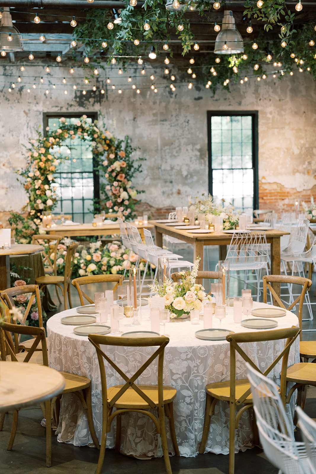 Reception set up at the Washington mill dye house with a mix of round and long guest tables and sweetheart table with a full floral arch backdrop.