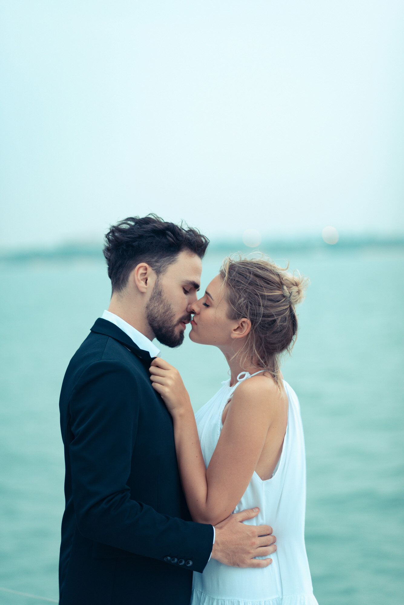 couple standing by the water, gently kissing