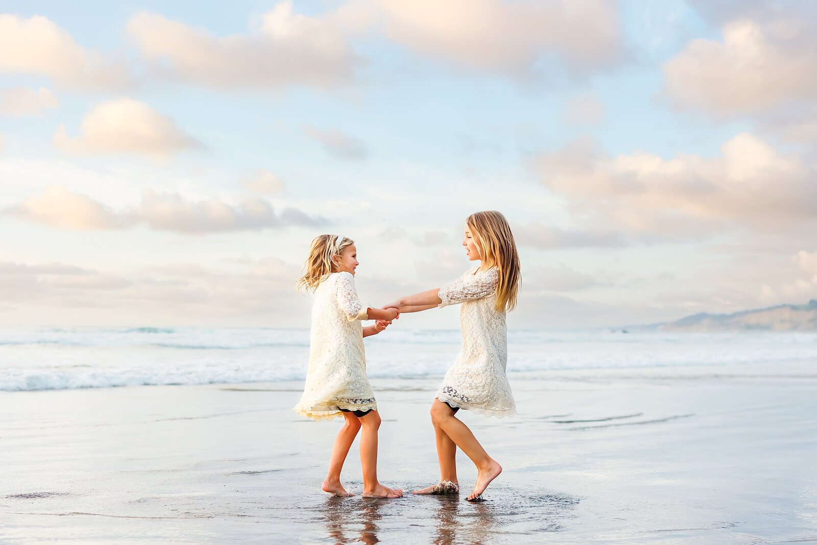 Sisters holding hands playing on the beach in La Jolla