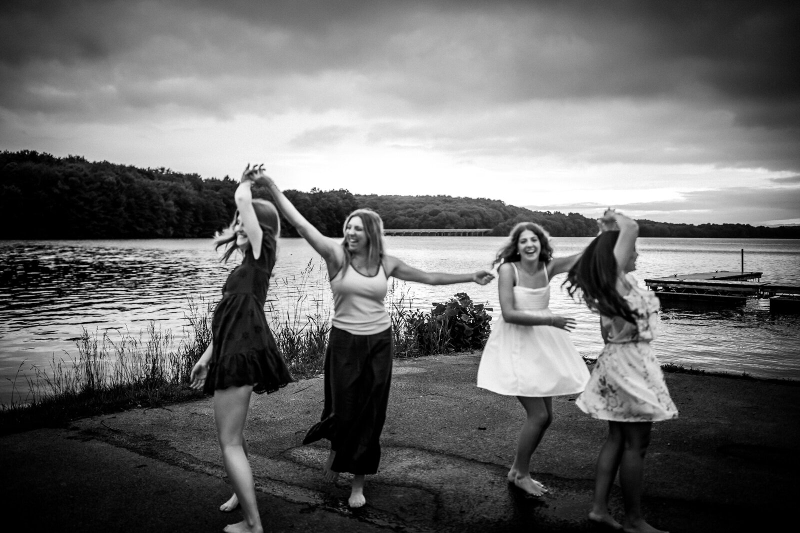 Striking black-and-white image four girls twirling by the dock