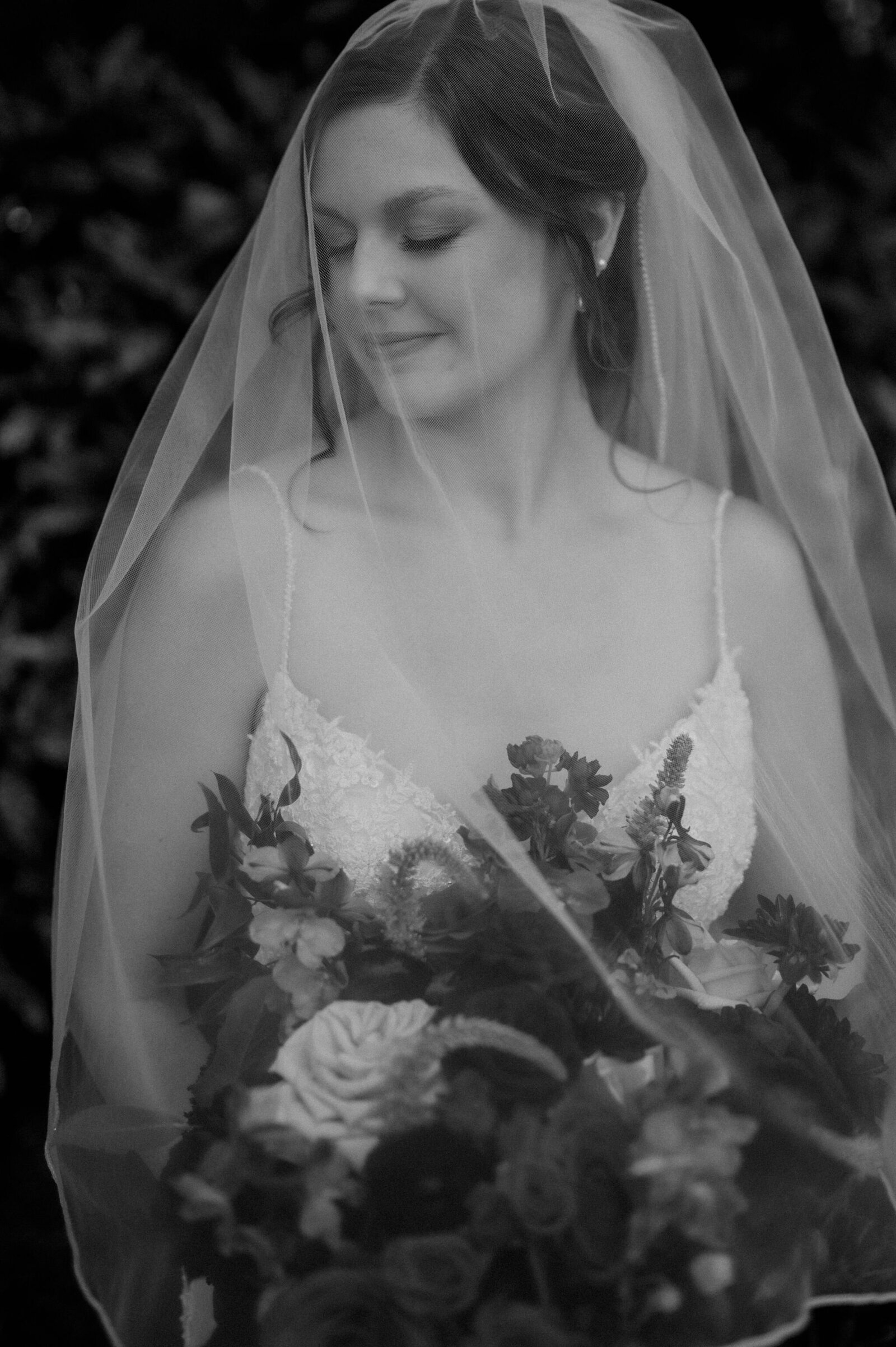 bridal portrait of bride with eyes closed and veil over face holding flower bouque