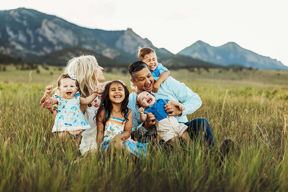 Family Photographer, family smiling and snuggling together in a field