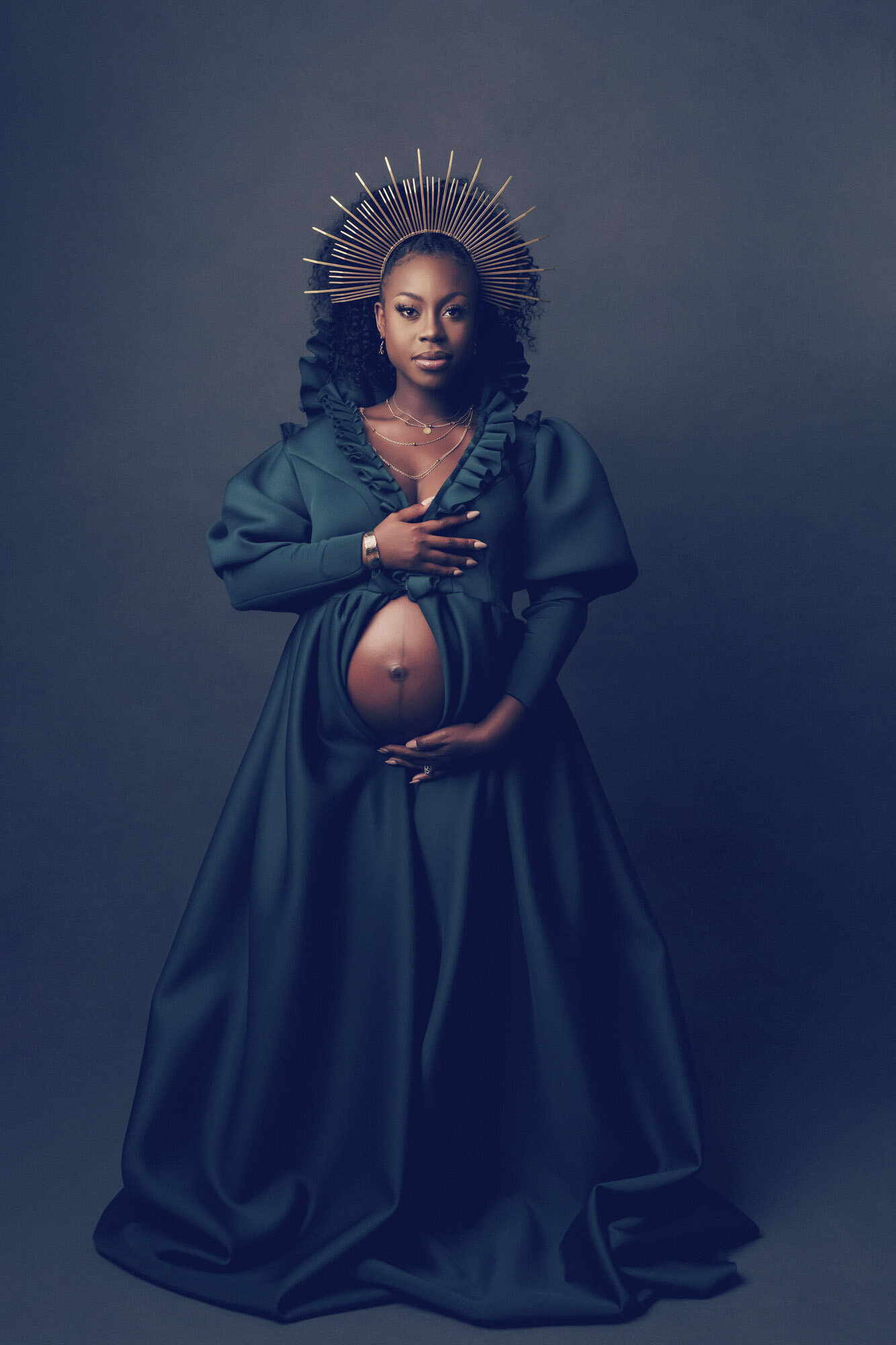 Maternity portrait of a woman in a large green dress, looking camera center.