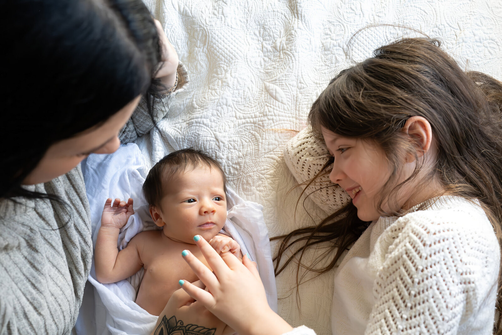 baby on bed between mother and sister in reno