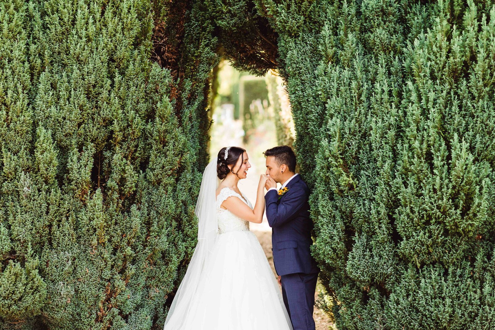 Bride and Groom portrait at their English Garden Wedding in Dorset, kissing under a hedge archway.