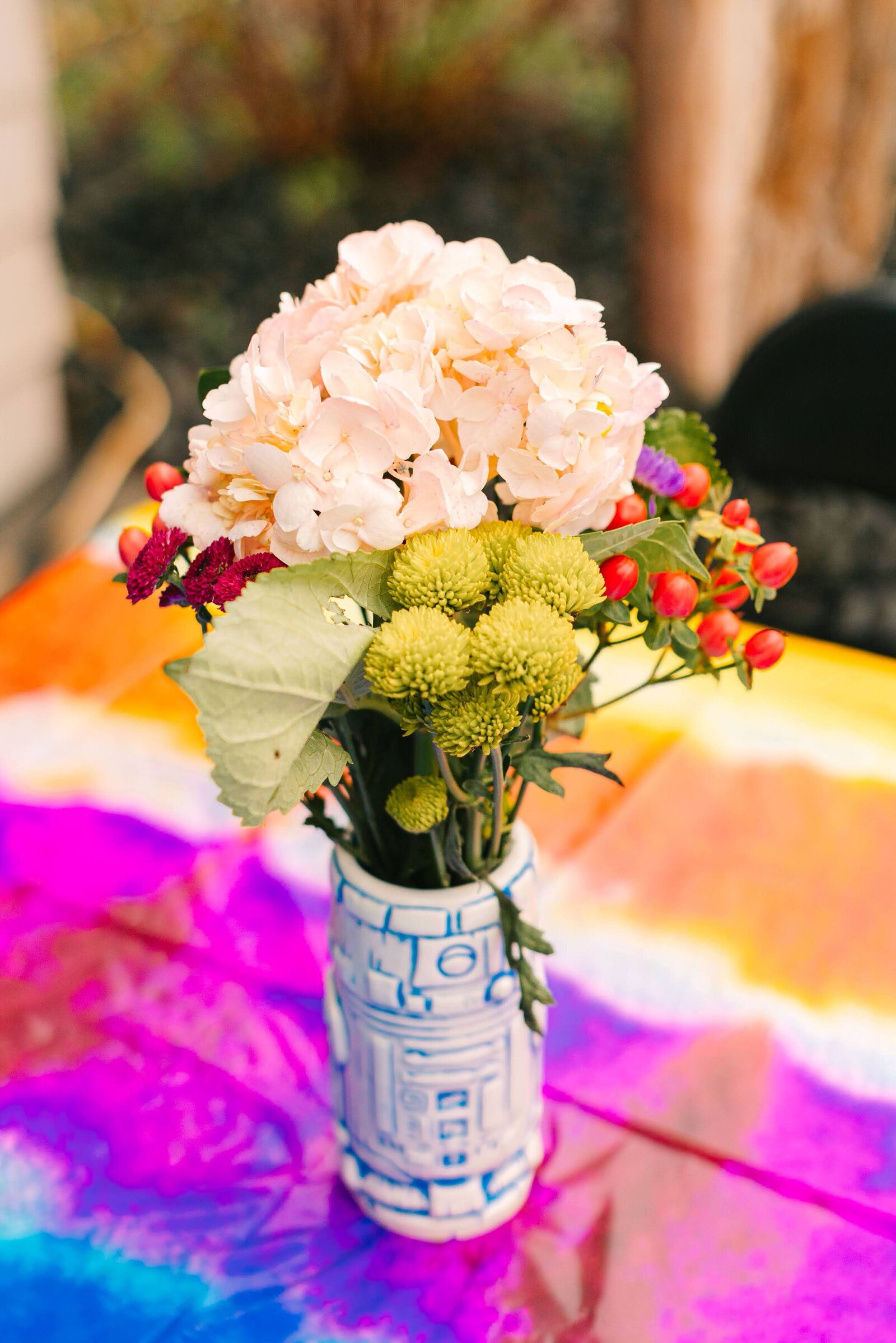 A small flower arrangement on a tie dye tablecloth.