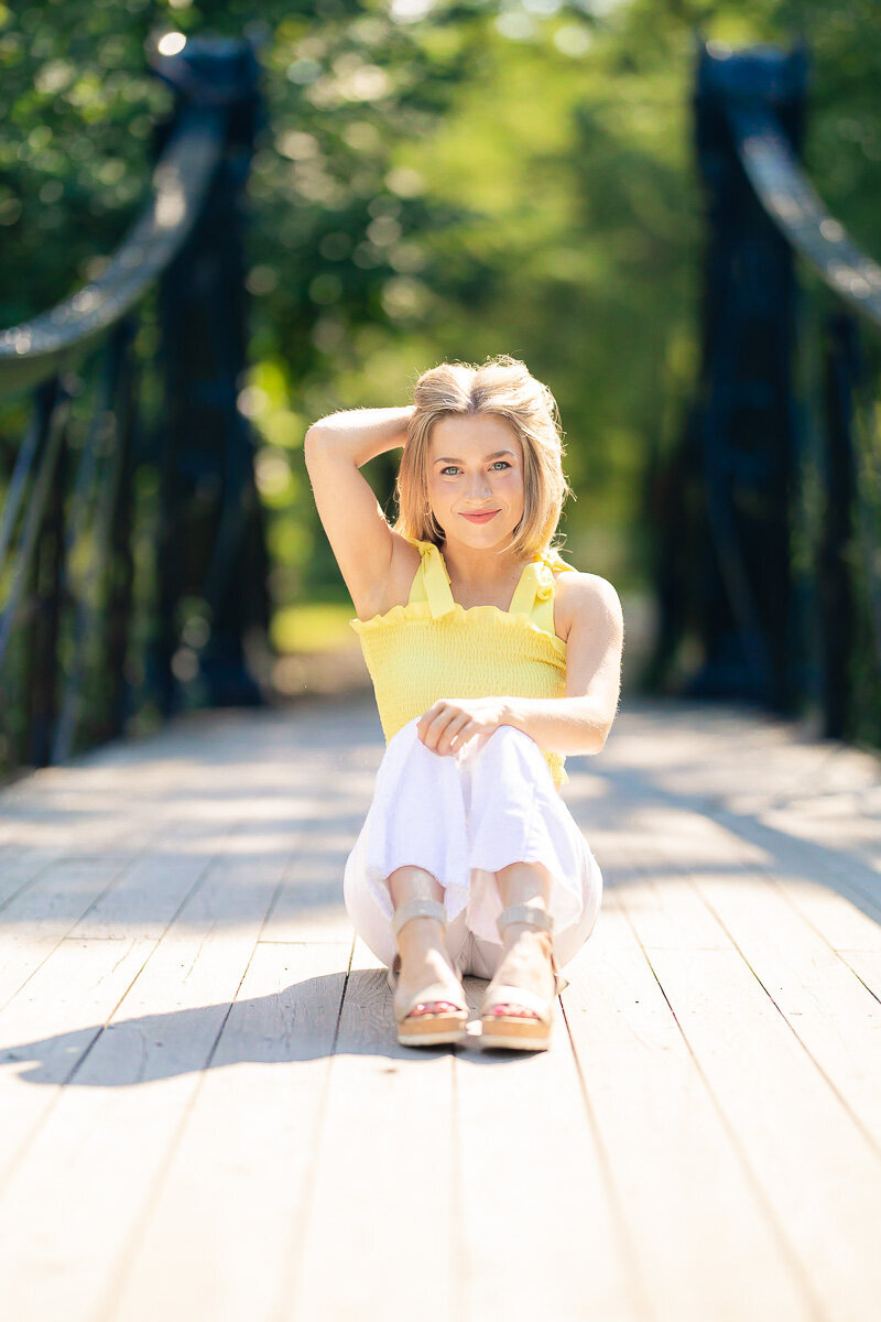 senior sitting on victorian bridge in forest park stl with hand holding her hair back