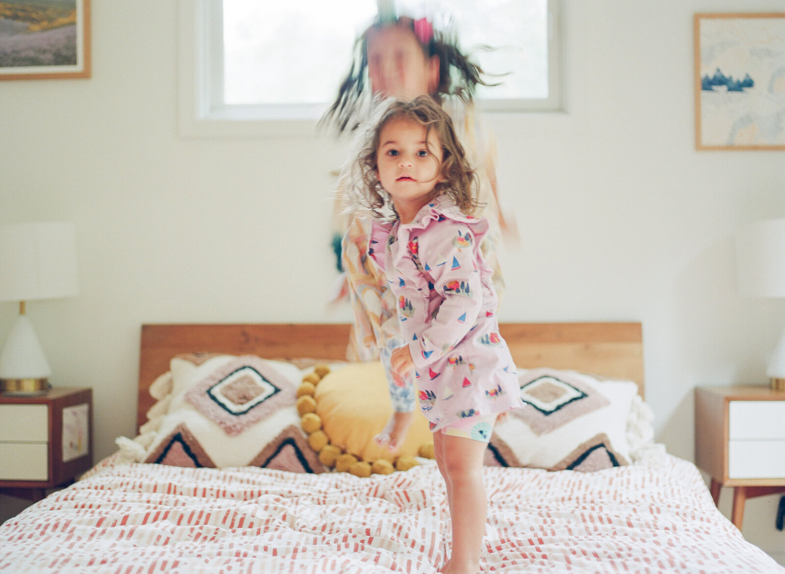 two young kids jumping on their parents bed