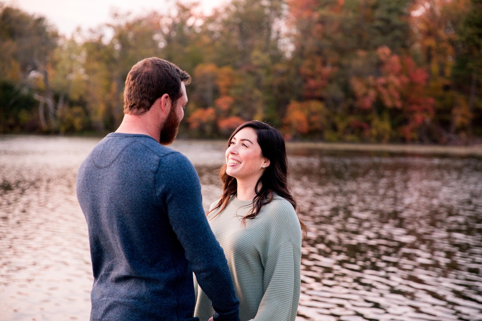 Couple looking at each other with fall colours in background.