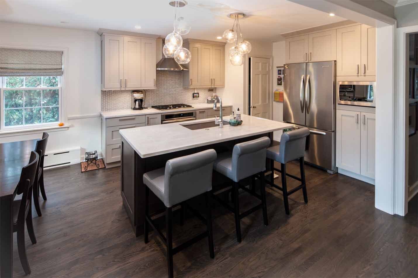 Modern kitchen with beige cabinets and white island with grey chairs