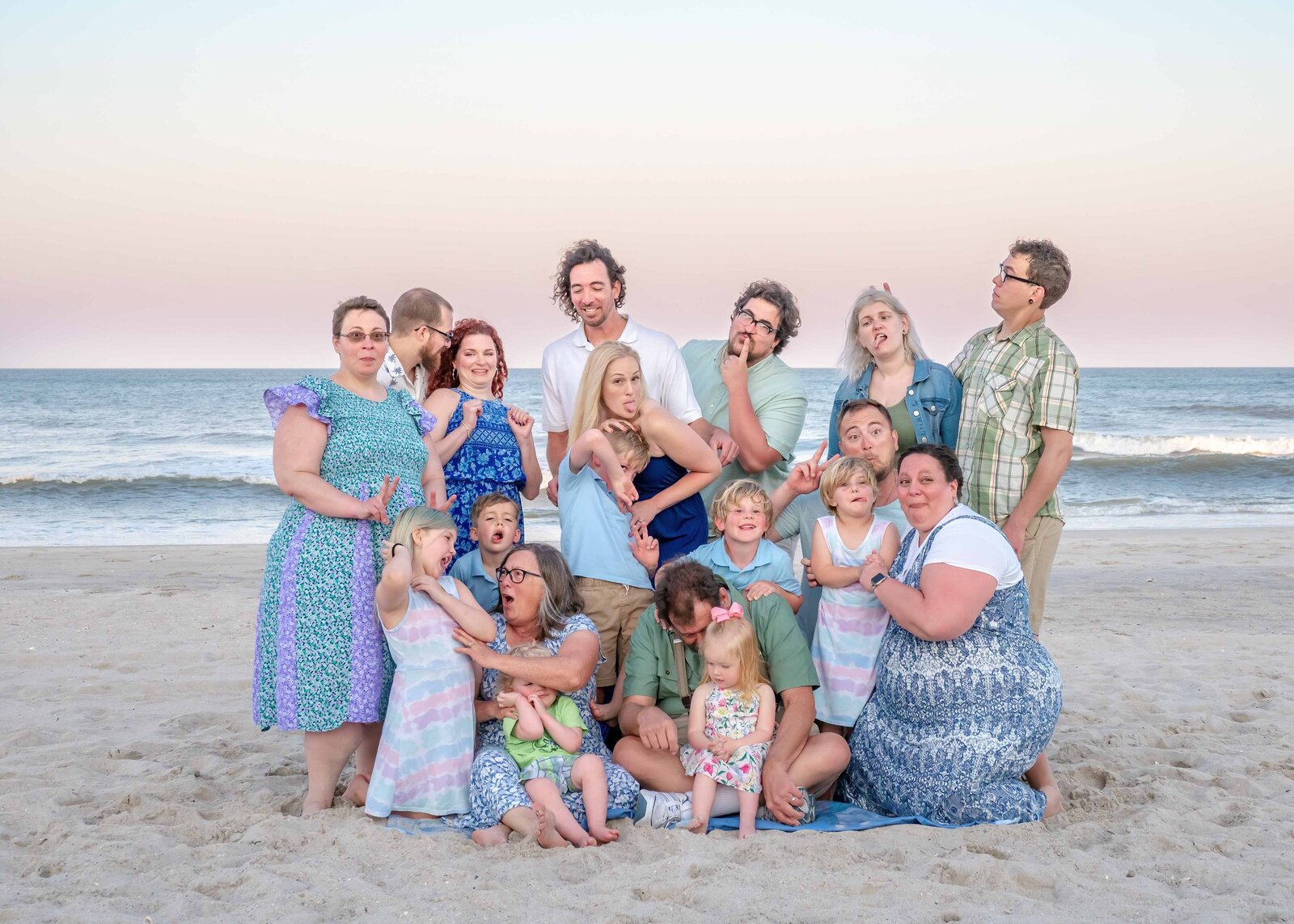 A large family gathers on the sandy shores of Ocean Isle Beach, expressing joy and playfulness. Dressed in a mix of casual and colorful outfits, they capture the lively spirit of a family reunion. Ideal for destination family photographer NC, highlighting multi-generational connections.