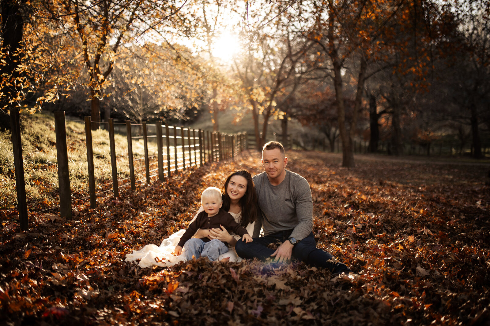 amily of four playing in a blanket of vibrant autumn leaves at Dolbel Reserve, Taradale, Hawke’s Bay – candid family photography capturing joyful moments amidst the golden hues of native bush, ideal for maternity, newborn, and family sessions in Napier and Hastings