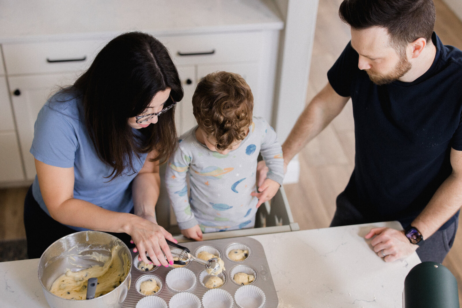 Mom, dad and son fill muffin pan with muffin mix at home in Odessa