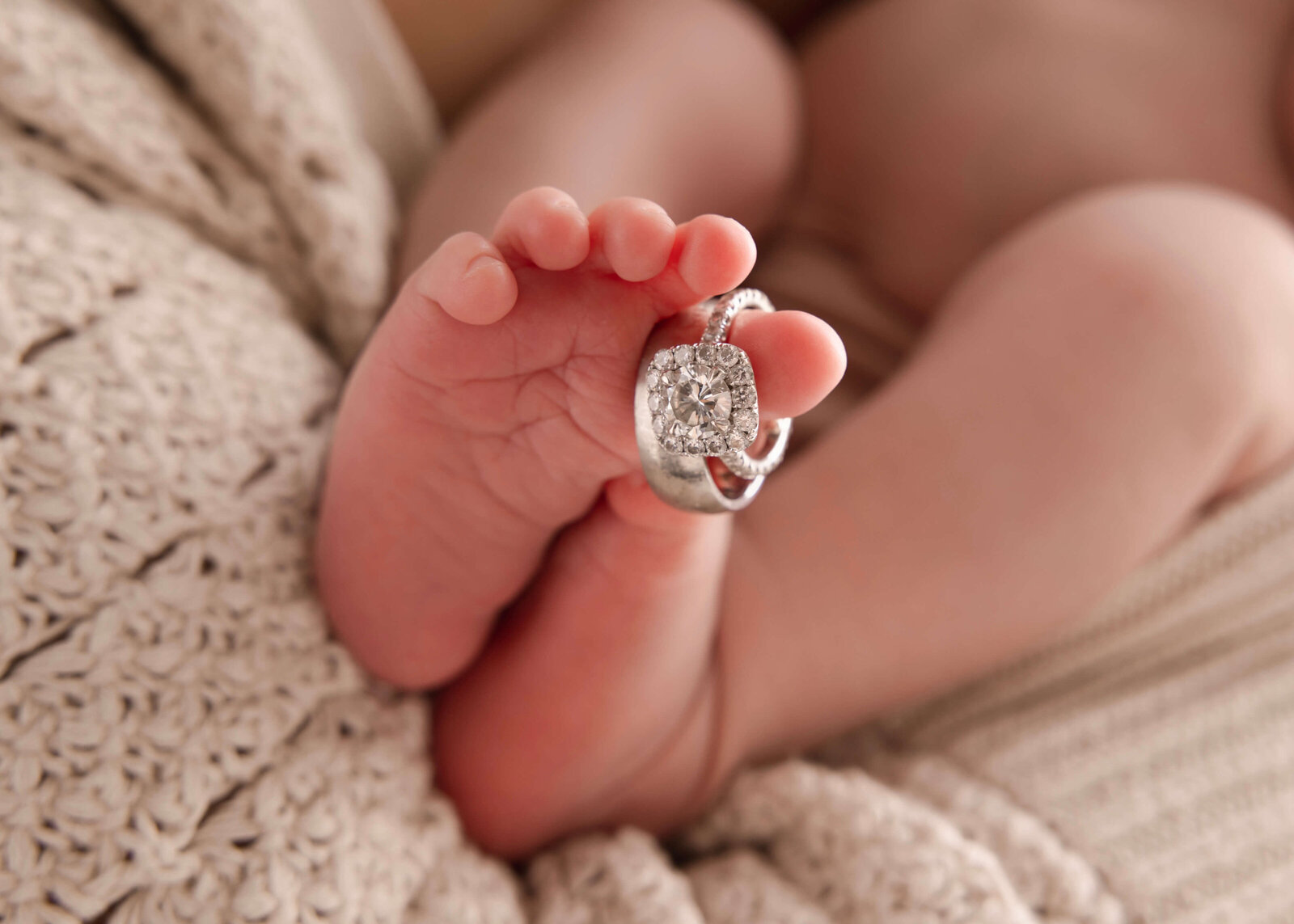 Detail shot of weddign rings posed on baby toes in studio by Ashley Nicole Photography
