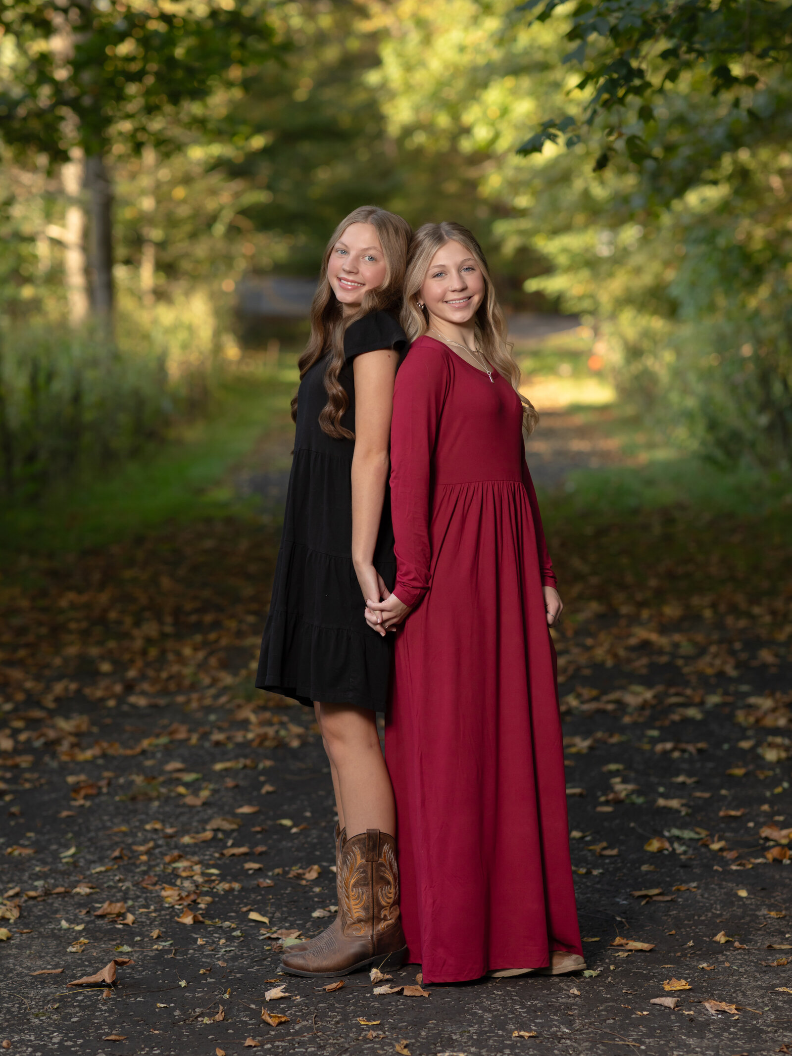 sisters holding hands posing for family photos in park