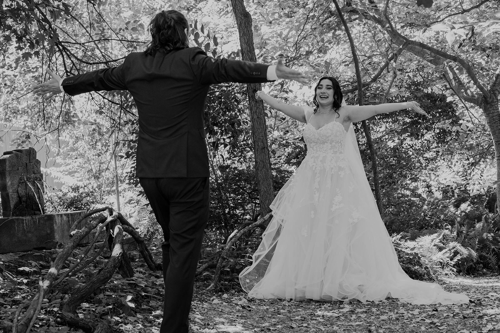 A bride and groom with their arms stretched out walk towards one another during the first look on their wedding day