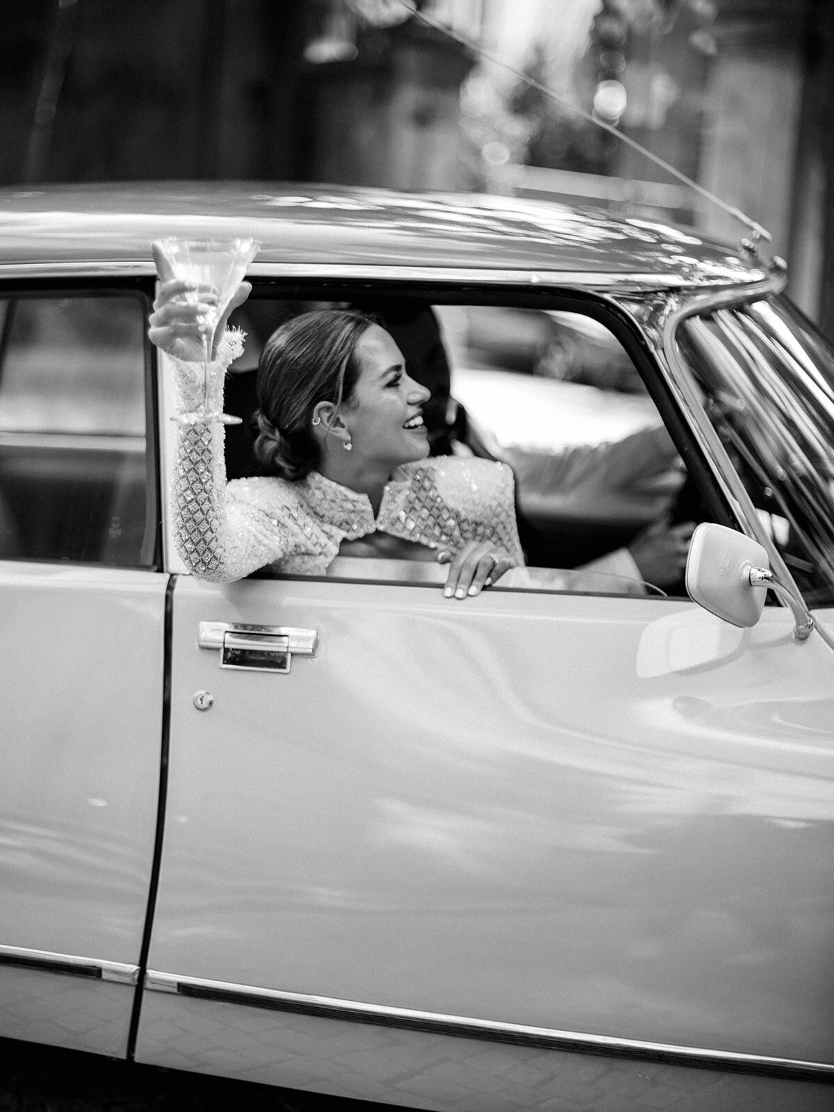 Bride on her getaway car as she holds martini glass