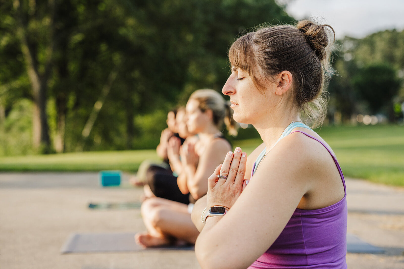 woman meditates during outdoor yoga class in boston